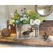 A wood moose box made with upcycled gray wood. A moose standing in the woods is wood-burned onto the front. It sits on a dining room table. 